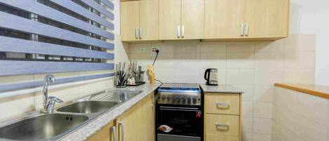 A compact kitchen with a sink, stove, and wooden cabinets.