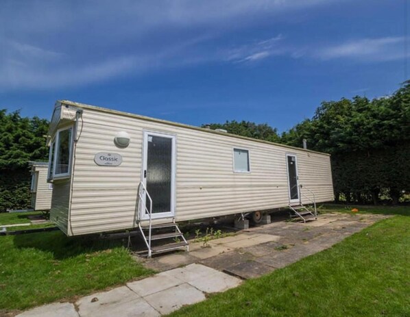 A classic mobile home with a small porch, a door, and a window. - Caravansleeps8-fireplace-petsok-golf-gym-pool (Skegness)
