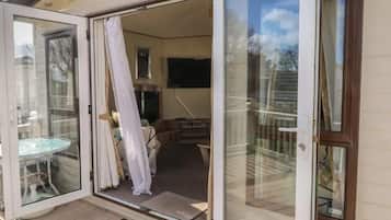 Una terraza de madera con un ventanal de vidrio que da a un espacio interior.