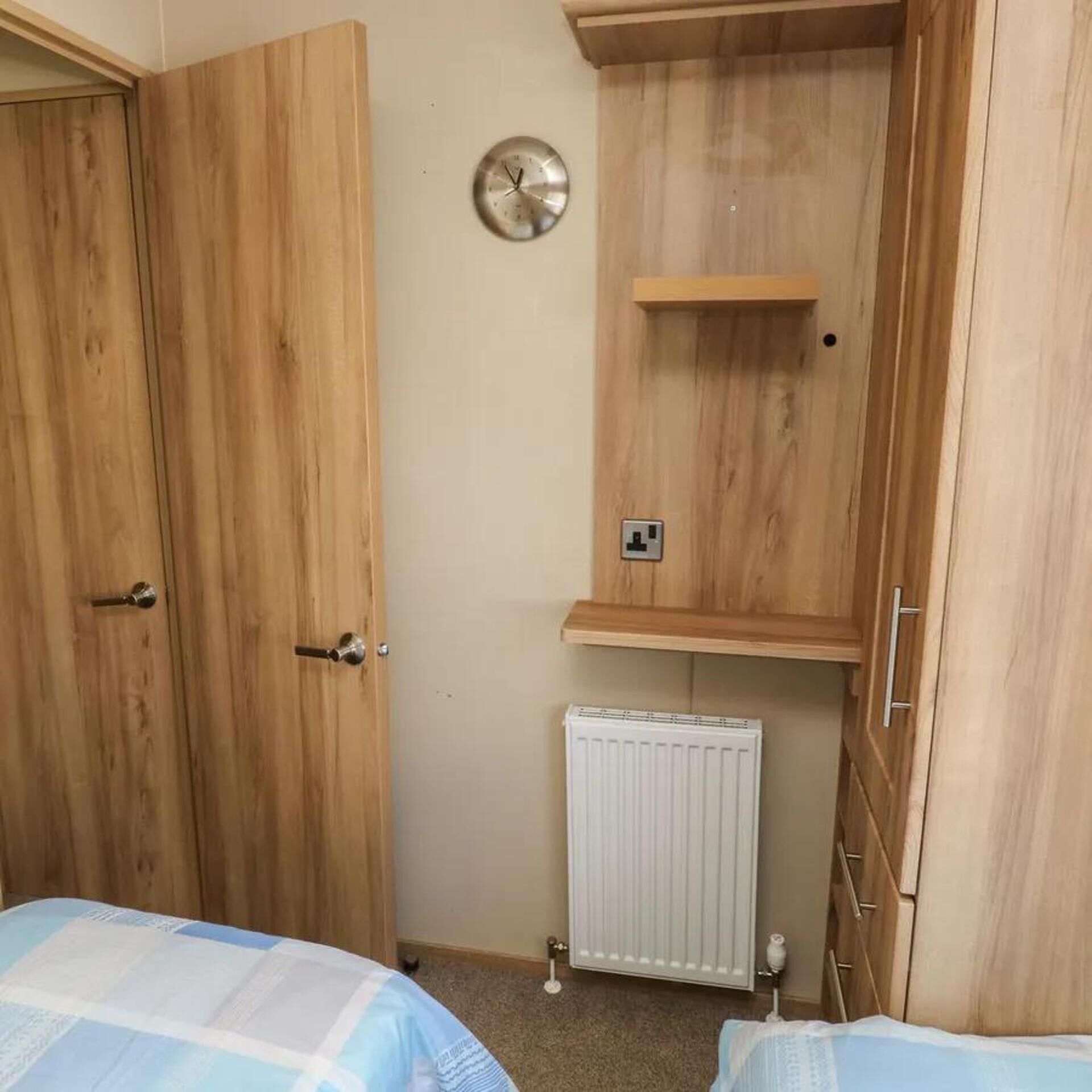 Quarto com armários de madeira, radiador e relógio na parede.