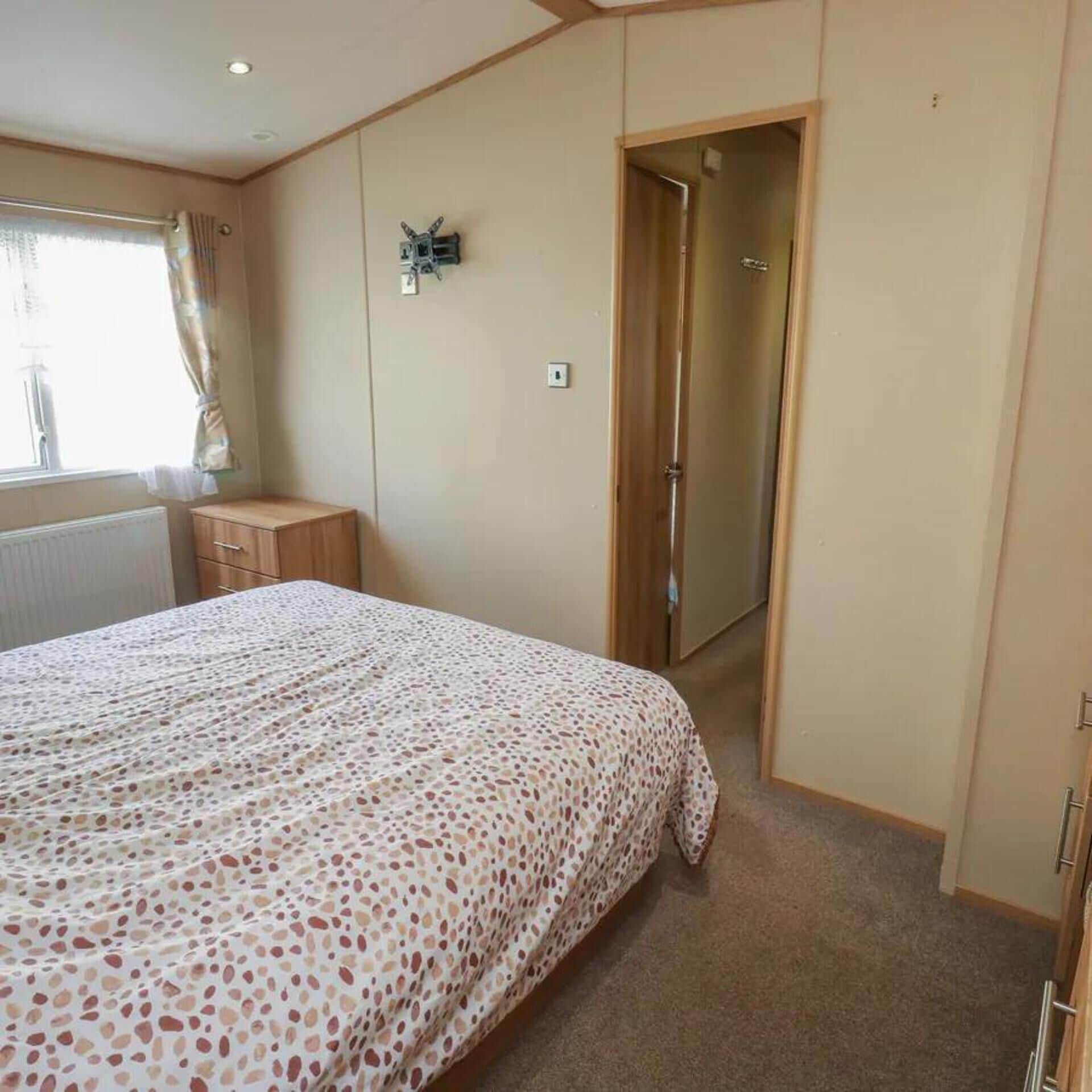 Une chambre à coucher comprenant un lit, une table de chevet, une armoire et une porte donnant sur une autre pièce.
