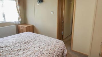 Une chambre à coucher comprenant un lit, une table de chevet, une armoire et une porte donnant sur une autre pièce.