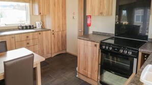 A compact kitchen with wooden cabinets, a black stove, and a window providing natural light.