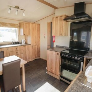 A compact kitchen with wooden cabinets, a black stove, and a window providing natural light.