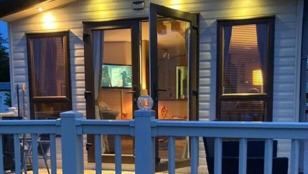 A small, single-story cabin with a deck, a covered outdoor seating area, and a visible door. - Caravansleeps6-freeparking-quietretreat-nature (Paignton)