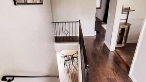 A staircase with a handrail, wooden steps, and a wall with a geometric painting. - Our Home Away From Home! (Lansing)