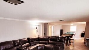 A spacious living area with a large L-shaped leather sofa, a dining table, and a pool table. - Our Home Away From Home! (Lansing)