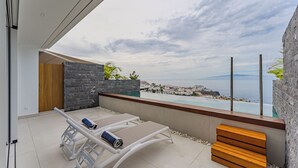 A modern balcony with a view of the sea, a pool, and a wooden bench. - Maravilloso Triplex con Pisicna Privada, Jacuzzi y Sauna en los Gigantes (Santiago del Teide)