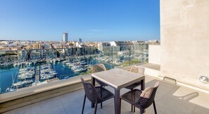 A balcony with a table and chairs overlooking a marina with boats and a cityscape in the background. - Modern 3BR home with Stunning Marina View in Pieta (Tal-Pietà)