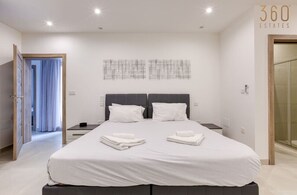 A modern bedroom with a large bed, two bedside tables, and a wall-mounted artwork. - Modern 3BR home with Stunning Marina View in Pieta (Tal-Pietà)