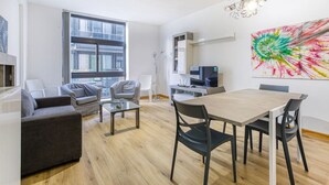 Ein modernes Wohnzimmer mit Essbereich, großen Fenstern und einem farbenfrohen abstrakten Gemälde.