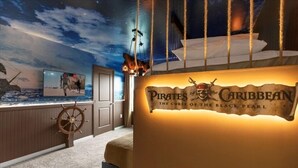 Ein Zimmer im maritimen Stil, darunter ein Schiffsschwester, ein Wandbild mit einem Piratenschiff und ein Schild mit der Aufschrift 'Pirates of the Caribbean: The Curse of the Black Pearl'.