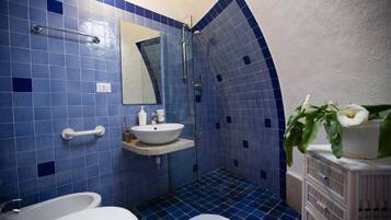 Un bagno con piastrelle blu, un lavandino bianco, uno specchio, una doccia e un water bianco.