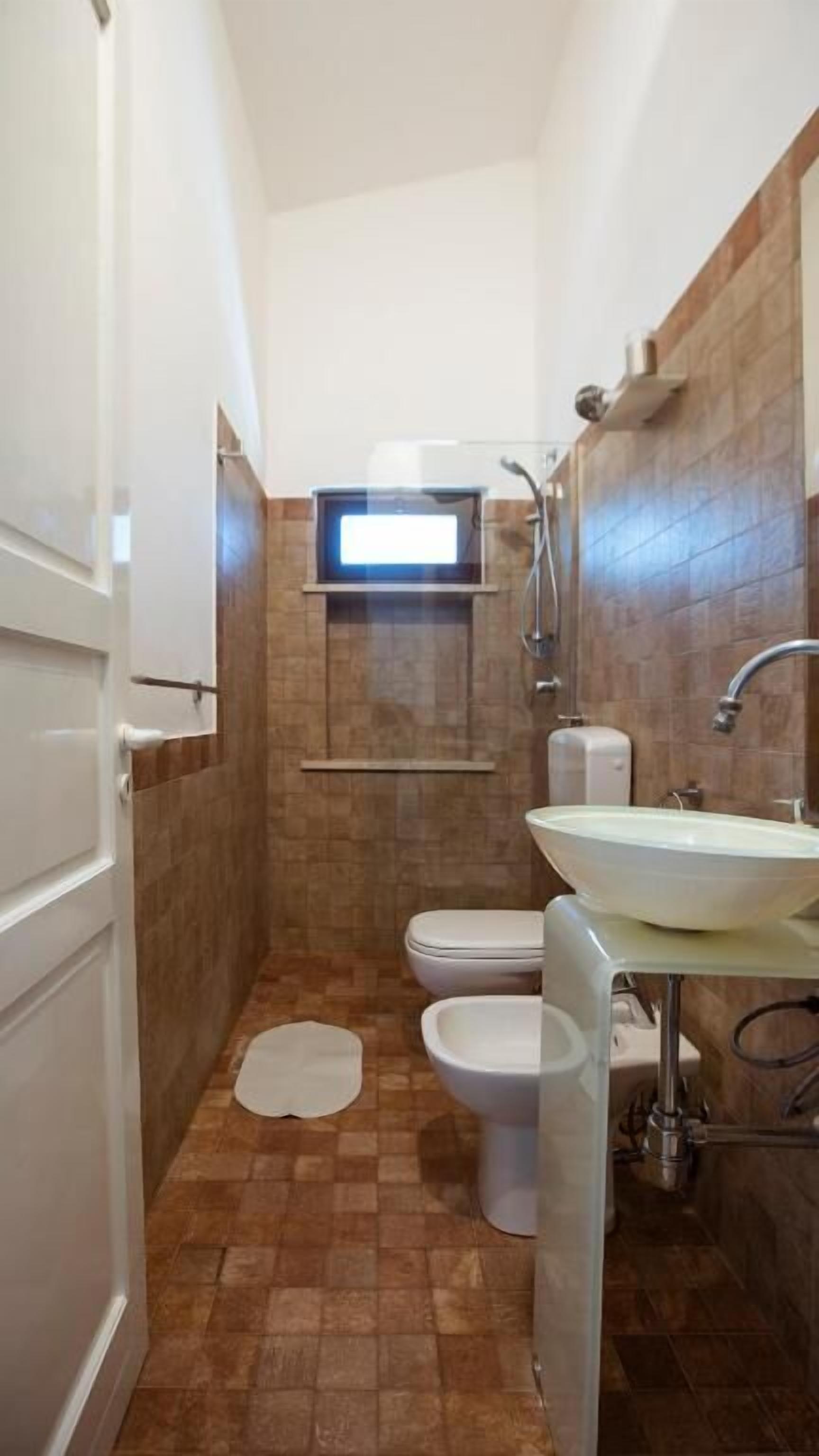 A small bathroom with a toilet, sink, and shower.