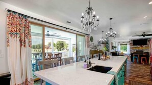 A kitchen with a large island, pendant lights, and a view to the outdoors.