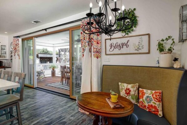 Un comedor con una mesa de madera, un sofá con cojines estampados y una araña.
