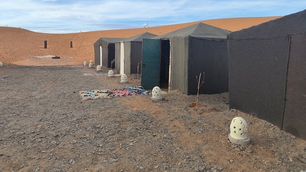 A desert landscape with tents and a small building. - Berber Desert Camp (Taouz)