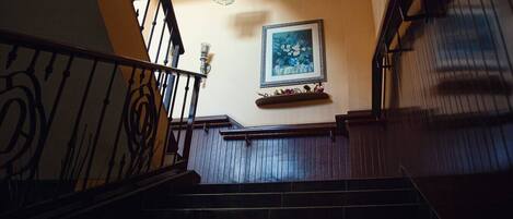 A wooden staircase with a black railing and a decorative light fixture above.