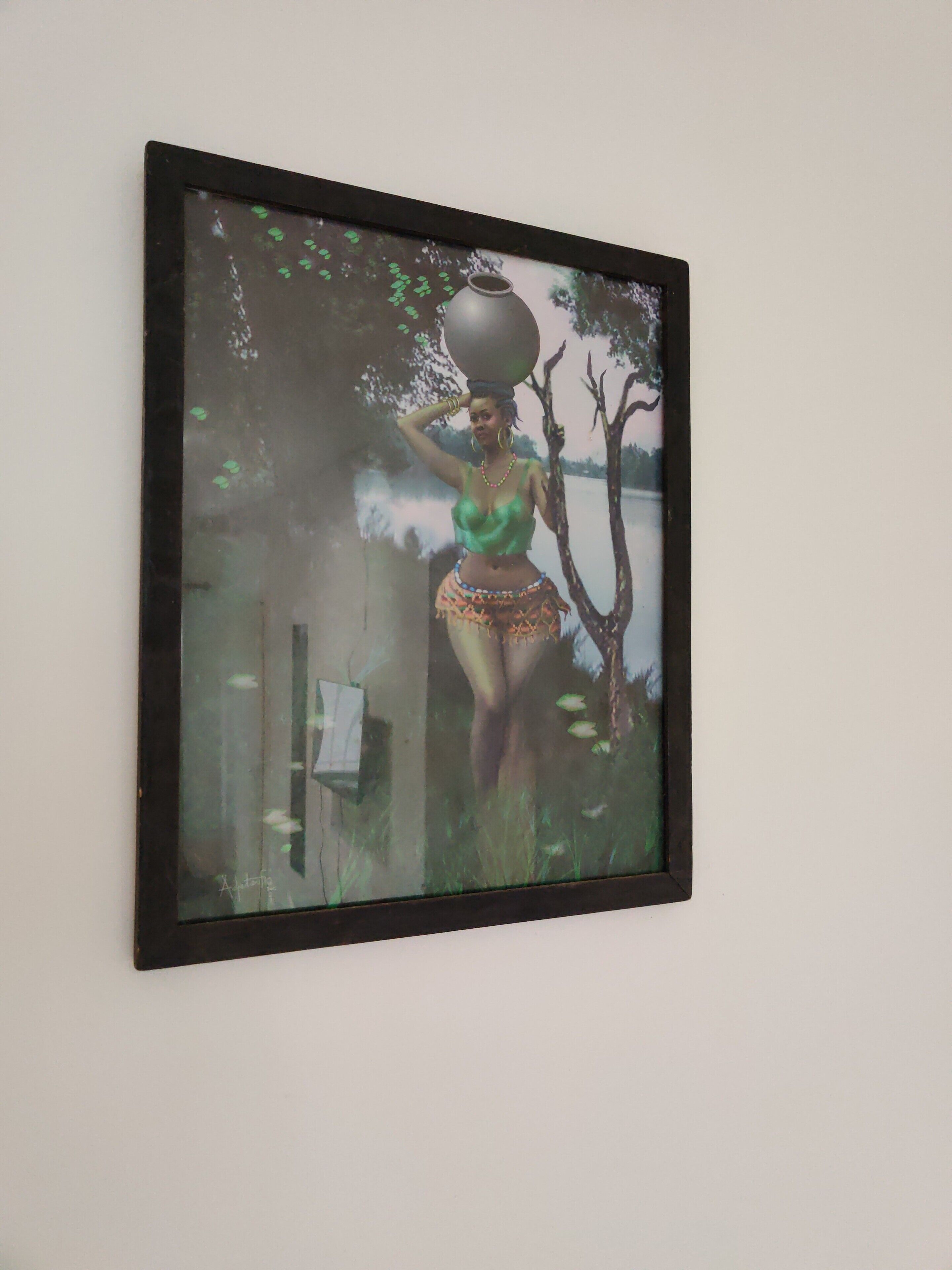 Ein gerahmtes Kunstwerk, das eine Frau zeigt, die eine Tonne auf ihrem Kopf trägt, vor einer Wand.