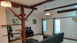Una sala de estar con una escalera de madera, un sofá, un televisor y obras de arte en las paredes.