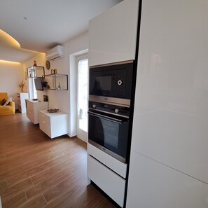 Una cocina moderna con electrodomésticos integrados, un rincón comedor con una silla amarilla y suelo de madera.