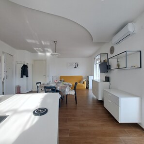 Una cocina moderna con comedor, un sofá amarillo y un refrigerador blanco.