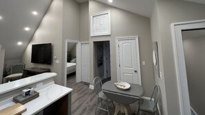A compact, modern kitchen with a skylight, a dining area with a table and chairs, and a TV mounted on the wall. - Fantastic Location (Ogunquit)