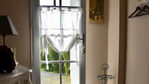 Een kamer met een witte deur, een klein tafeltje met een lamp en een metalen kapstok.