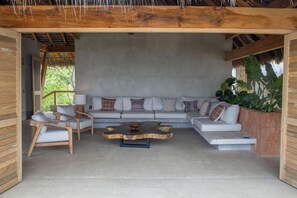 Un espacio de descanso al aire libre con techo, un sofá, dos sillas y una mesa de centro.