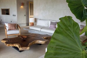 A modern living room with a sofa, armchair, and a unique wooden coffee table.