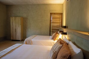 A bedroom with two beds, a wooden wardrobe, and a window with blinds.