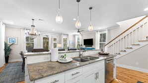 A modern kitchen with granite countertops, white cabinetry, a central island, and pendant lighting.
