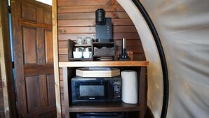 A compact kitchenette with a microwave, coffee maker, and storage shelves. - Modern_ Unique_Old West Wagon_Spacious_Views (Chilton)