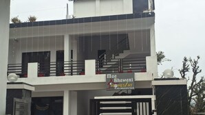 A two-story building with a sign for 'Maa Bhawani Homes/Day' and a contact number. - Maa Bhawani Homestay (Reasi)