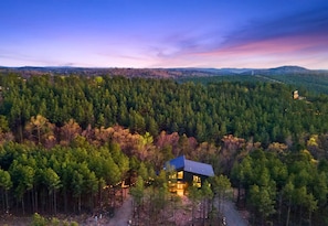 Eine abgelegene Holzhütte, umgeben von dichtem Wald, mit freiem Blick auf die umliegende Landschaft.