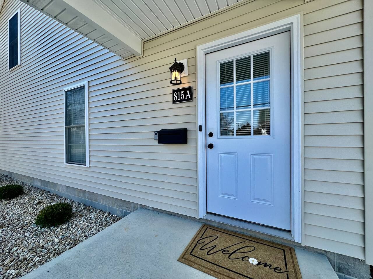 A house with a white door, a mailbox, and a welcome mat.