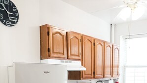 Een keuken met houten kastjes, een witte koelkast, een fornuis en een spoelbak.