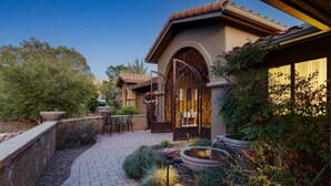 A courtyard with a patio, a fountain, and a gate.