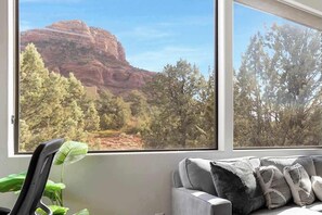 A room with a large window offering a view of a red rock formation and trees. - Mammoth Rock Lodge-New Family Home REMODELED, 2 Hot Tubs & Game Room (Sedona)