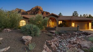 Ein Haus mit Terrasse, Garage und einem Berg im Hintergrund.