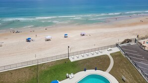 Vista de una playa con piscina, sombrillas y tumbonas.
