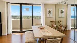 Un comedor con una mesa de madera, sillas acolchadas y vista al océano a través de amplios ventanales.