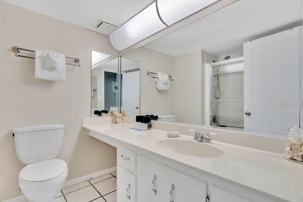 Une salle de bain moderne avec des toilettes blanches, un lavabo et un grand miroir.