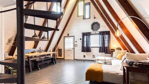 A loft-style bedroom with a wooden floor, a bed, a desk, and a staircase.