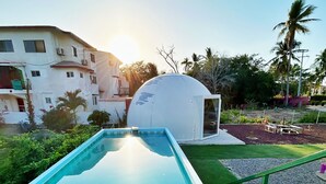 Une piscine offrant une vue dégagée sur une structure en forme de dôme et un bâtiment situé à l’arrière-plan.