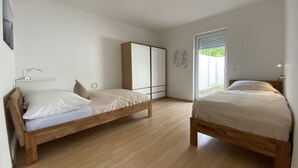 A bedroom with two wooden beds, a wardrobe, and a window with blinds. - Apartment in Schloß Nähe (Sögel)