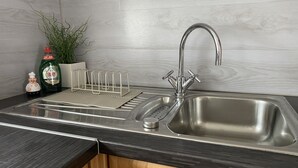 A modern kitchen with a stainless steel sink, a dish rack, and a bottle of Fairy dish soap. - Apartment in Schloß Nähe (Sögel)