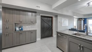 Una cocina moderna con armarios grises, una isla grande con un fregadero y una puerta de madera oscura.