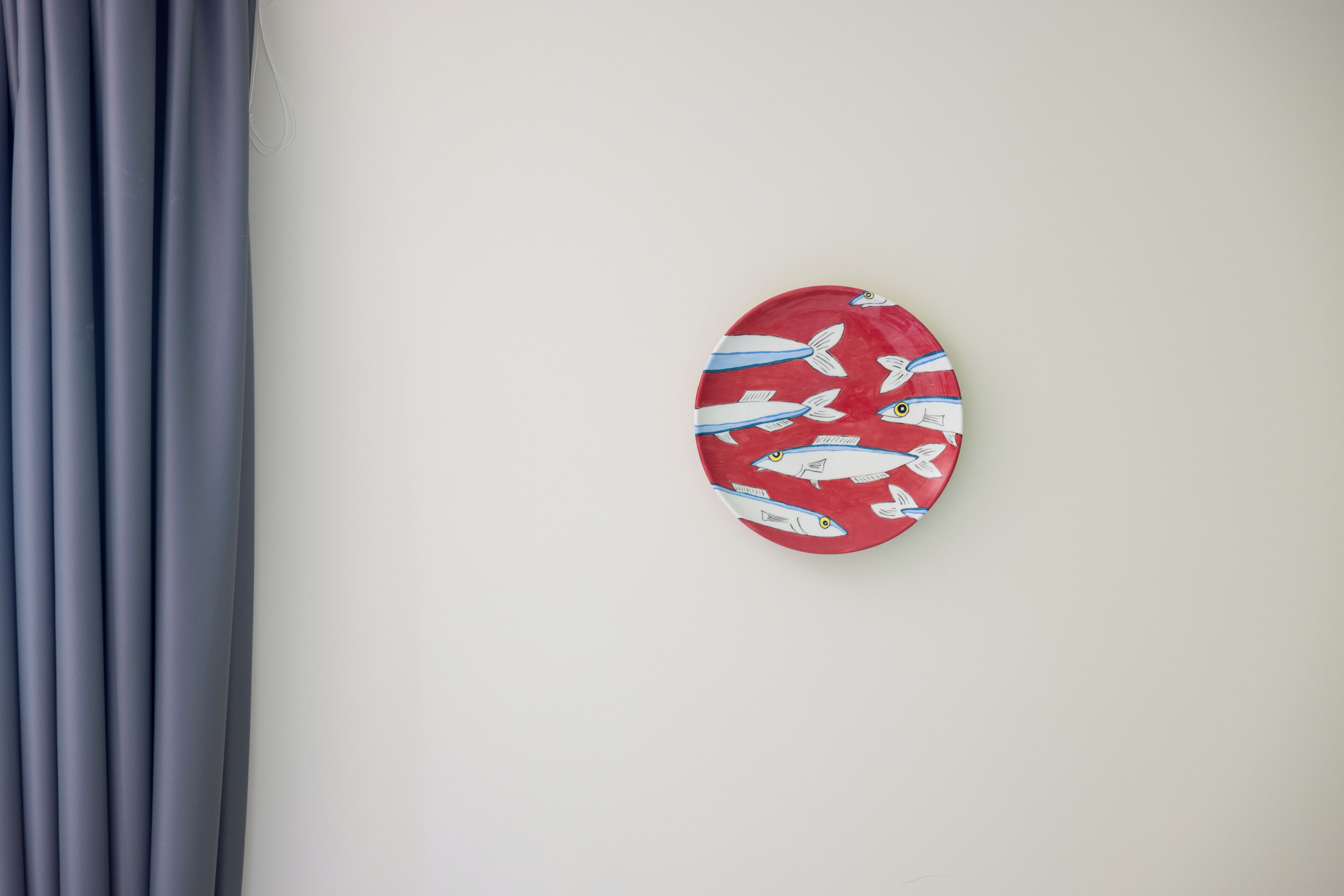 A wall with a red plate featuring fish patterns.