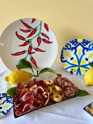 A table with a plate of cured meats, a lemon, and decorative plates with chili pepper designs. - Scario Club (San Giovanni a Piro)